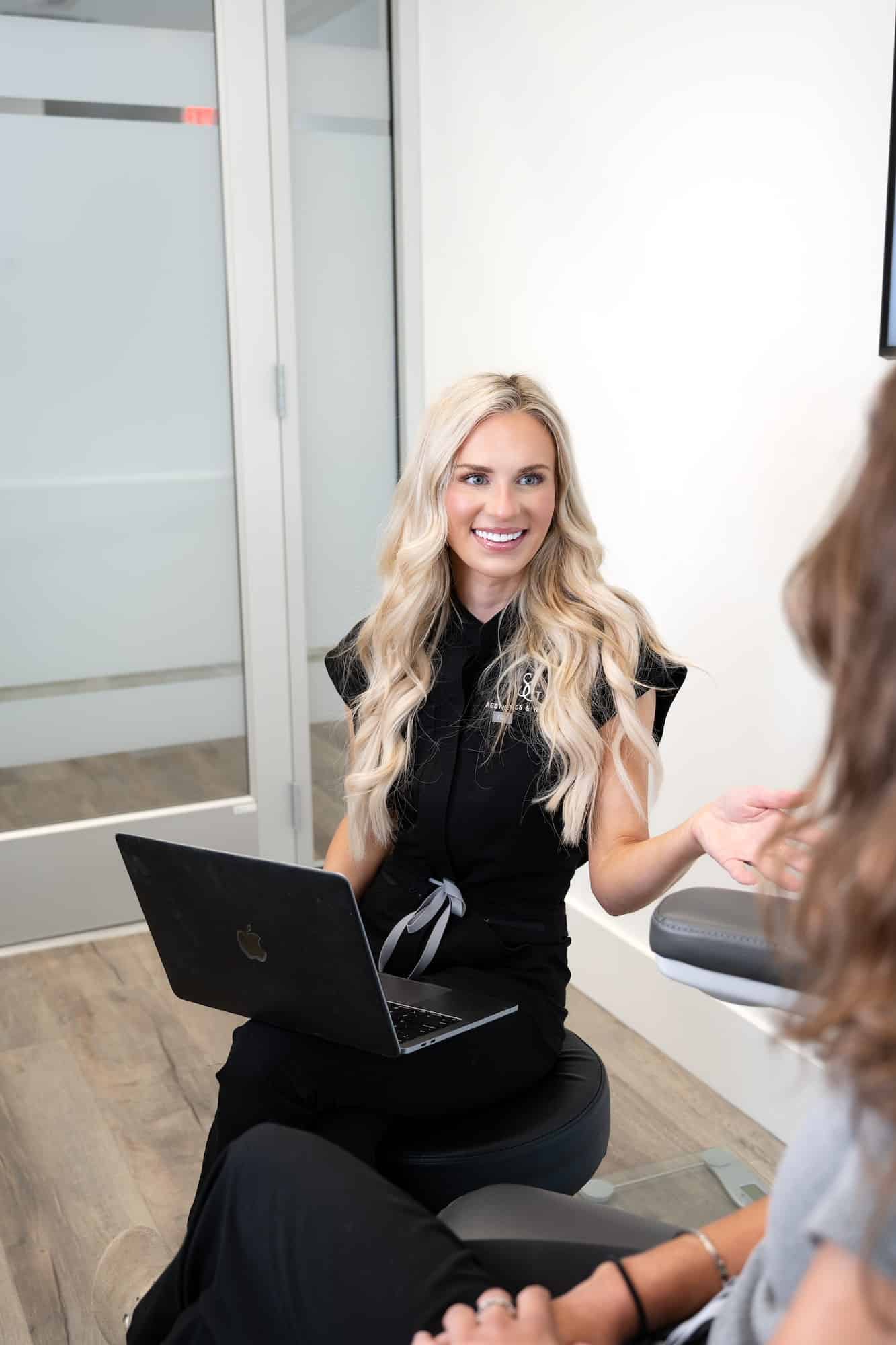 Provider consulting with patient and reviewing treatment plan on a laptop in a medical aesthetics clinic