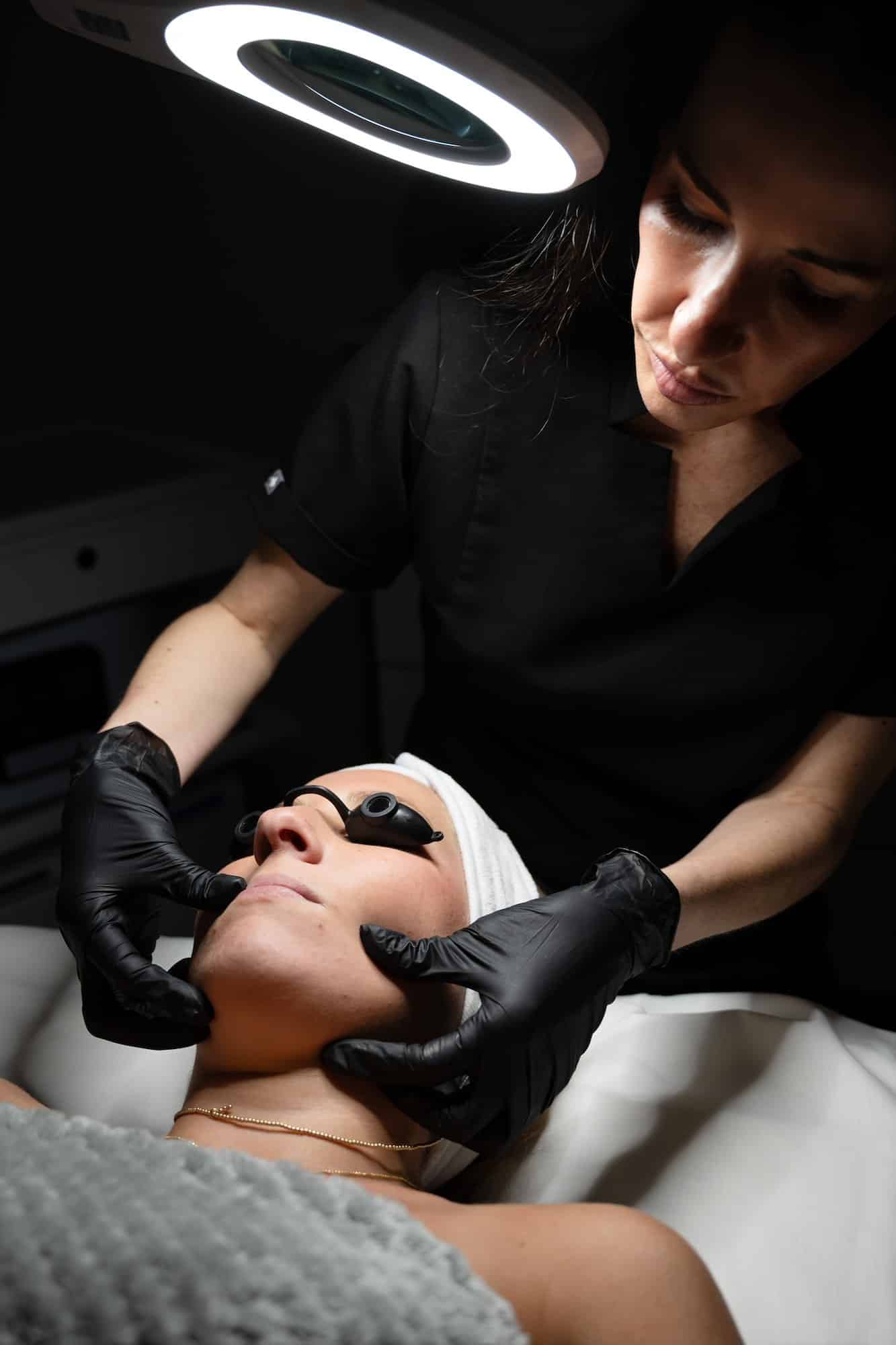 Provider performing a facial skin treatment under clinical lighting to enhance skin appearance