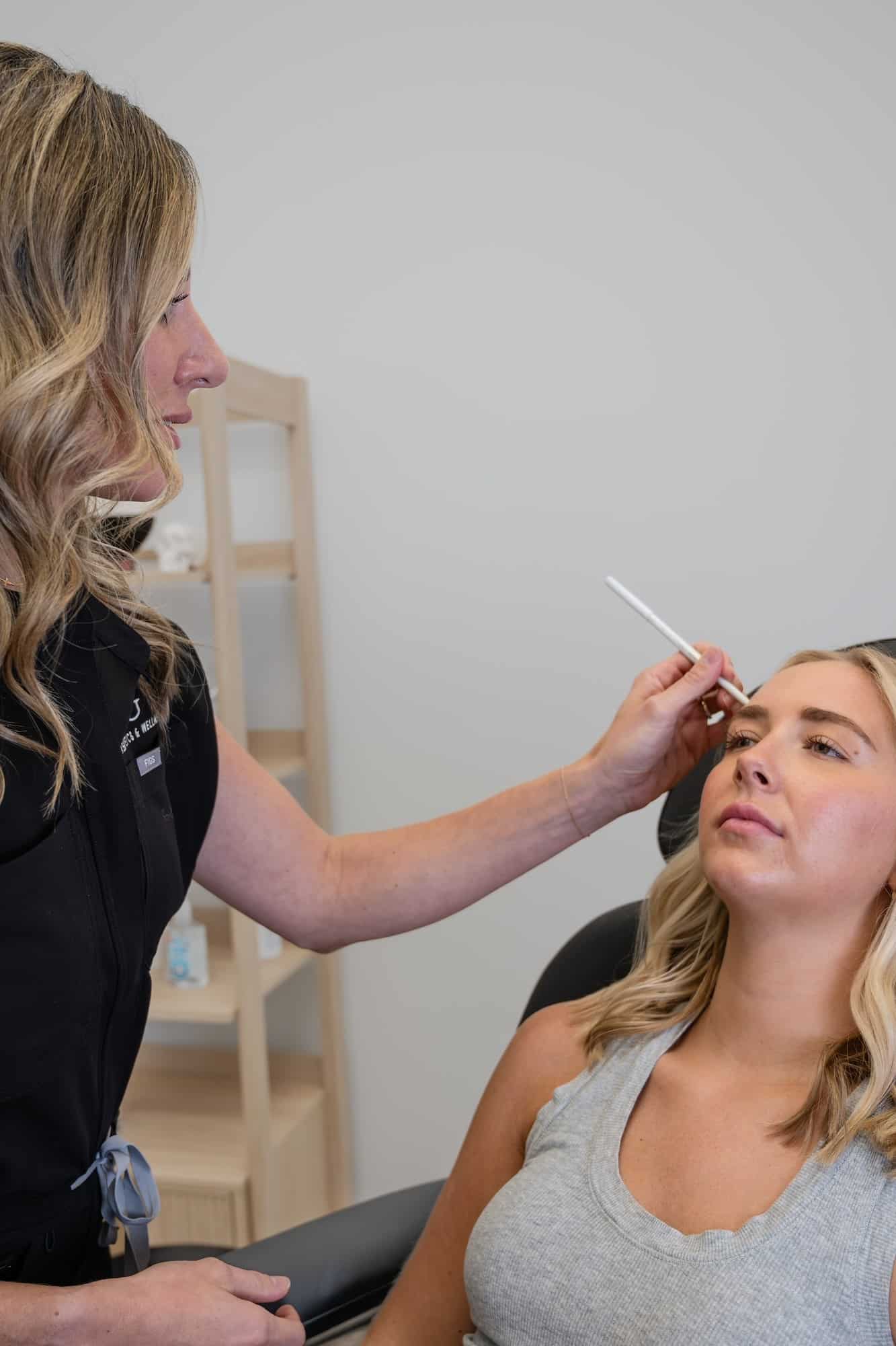 Aesthetic provider evaluating skin and preparing for a facial treatment in a clinical setting